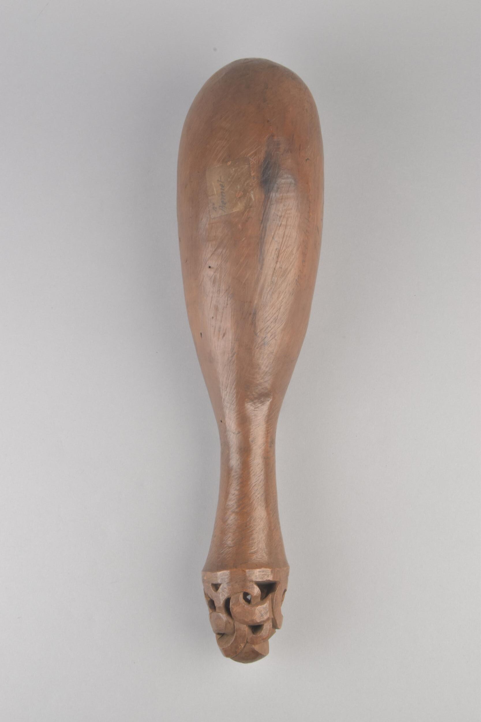 Top view of a carved wooden artifact with a bulbous body and intricately detailed handle, showcasing craftsmanship and design.