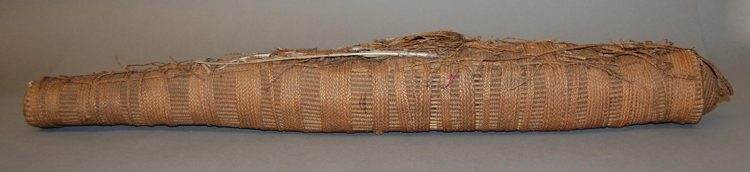 Close-up of a long, cylindrical woven object made from natural fibers, showcasing intricate patterns and textures.