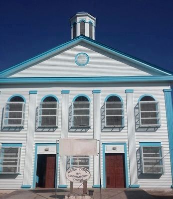 A bright blue and white church building with arched windows, featuring a central dome and a sign for a congregational church.