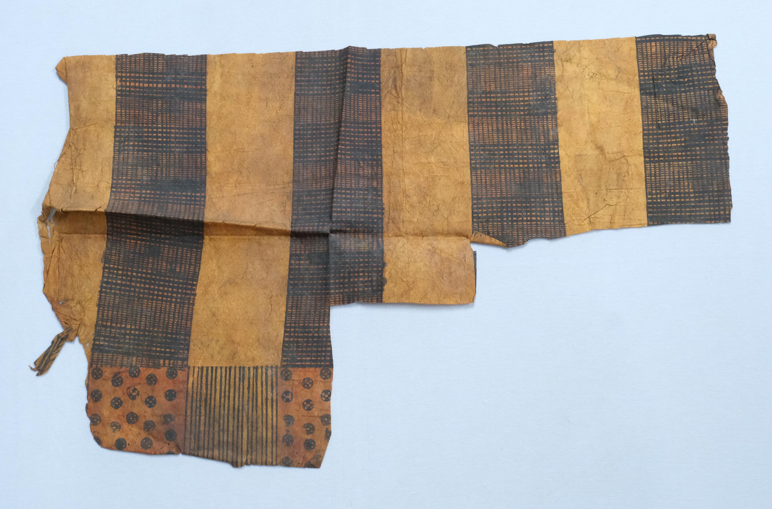 A piece of ancient fabric featuring alternating stripes in dark brown and tan, showcasing intricate patterns and textures.