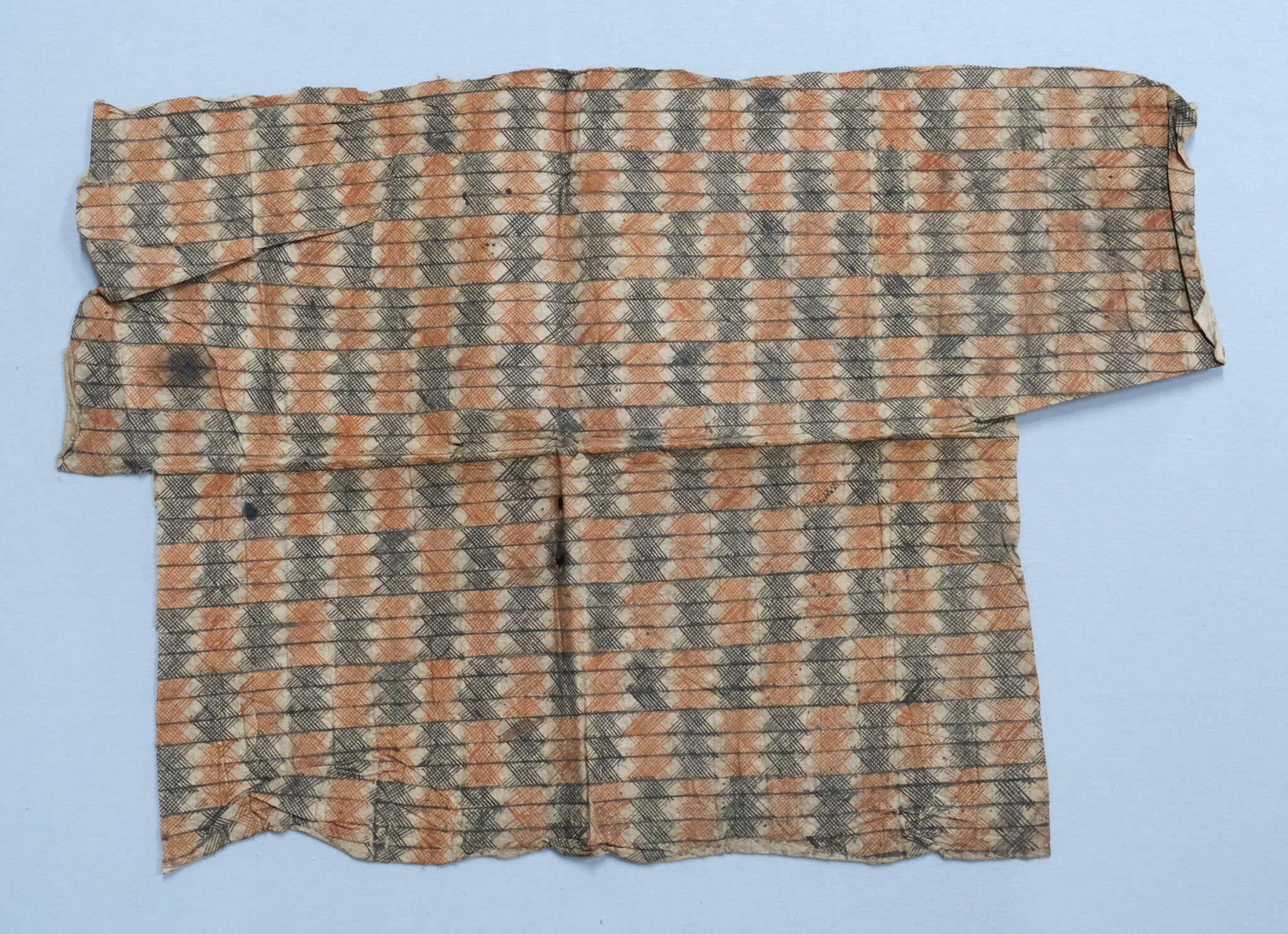 A folded textile featuring repeating patterns of orange and black stripes.