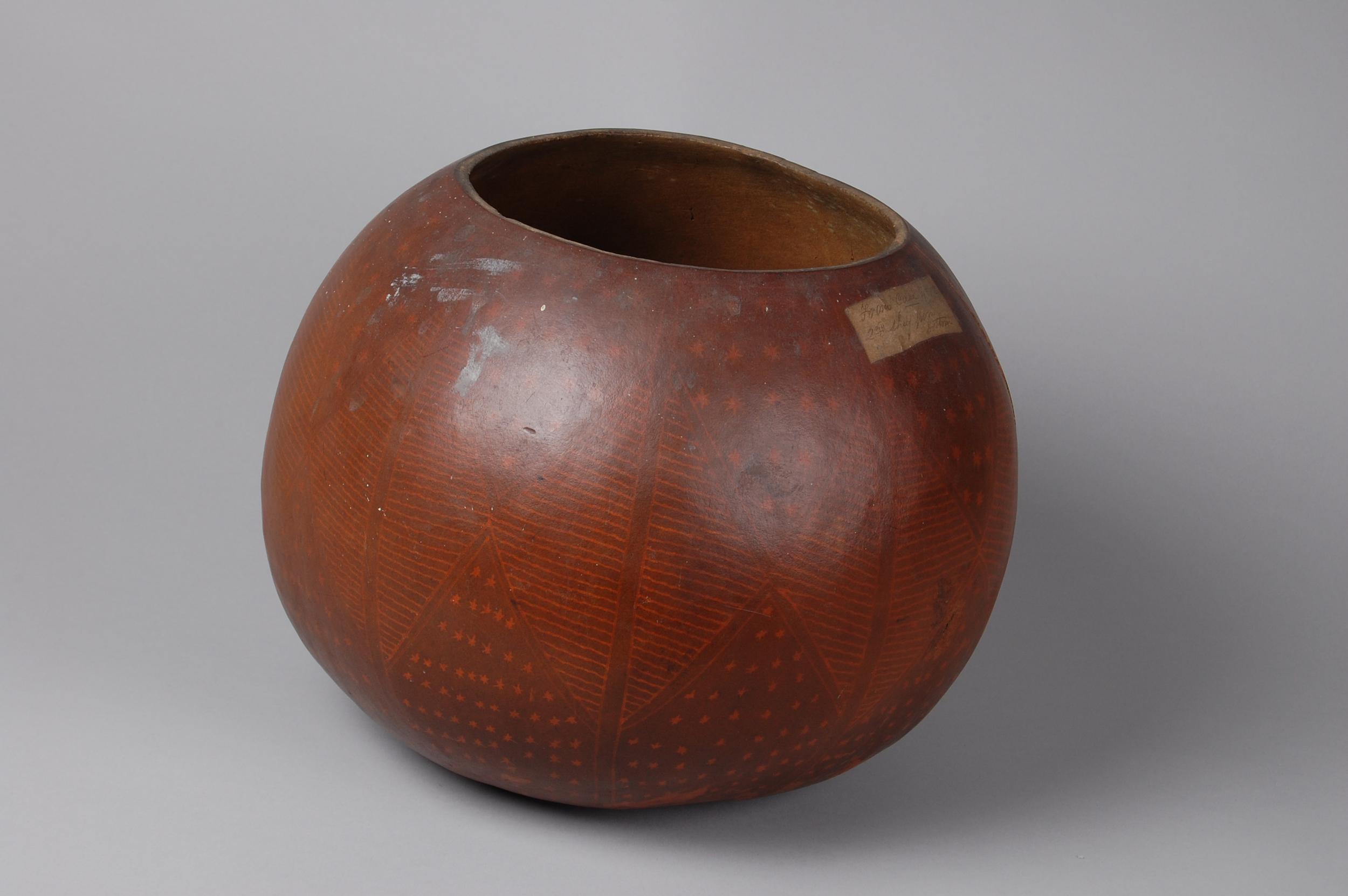 Round, reddish-brown pottery bowl featuring geometric patterns and a smooth finish.
