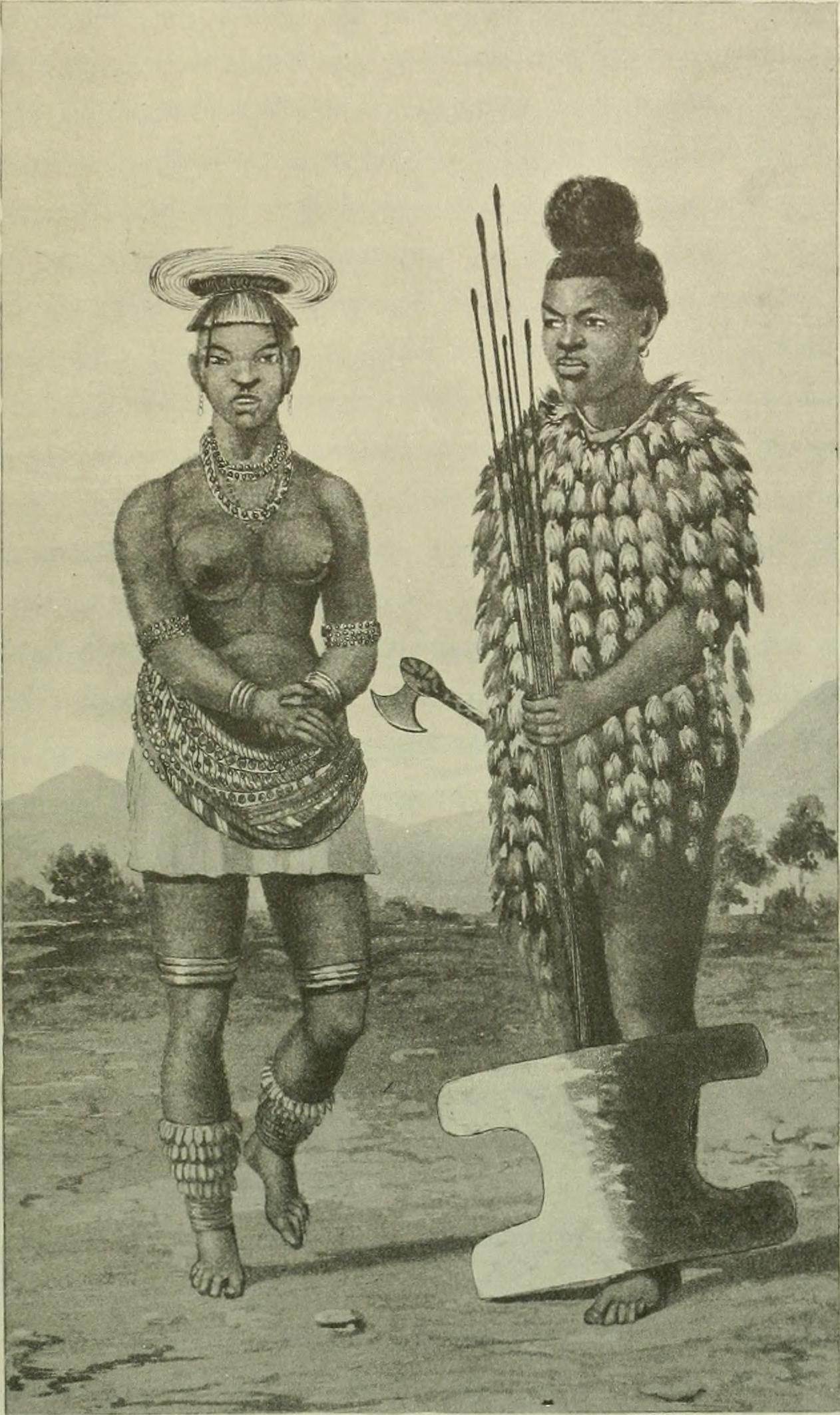 Two individuals in traditional attire stand together on a landscape, one holding a spear and the other an axe, adorned with jewelry.