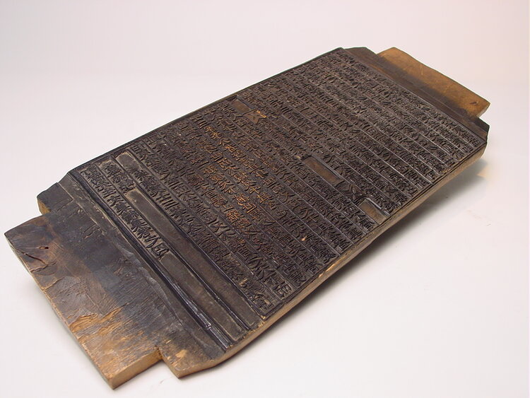 A wooden printing block engraved with intricate text, likely used for traditional printmaking or calligraphy.